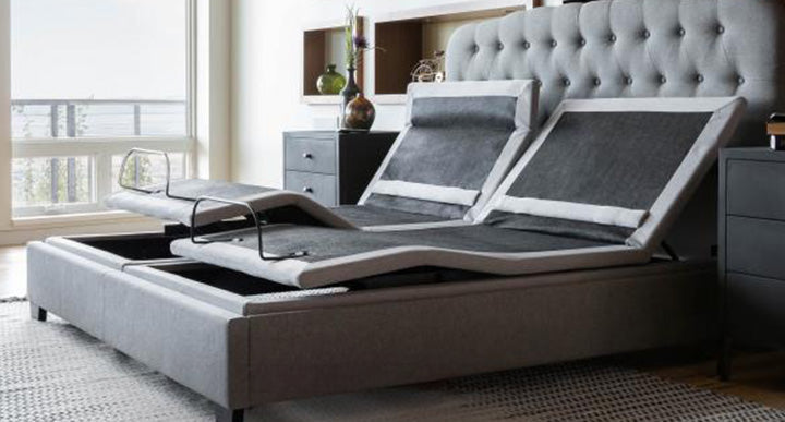 A modern adjustable bed with a tufted headboard, shown in an elegant bedroom with large windows.