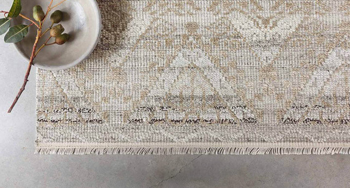 Close-up of a beige patterned rug with a decorative bowl